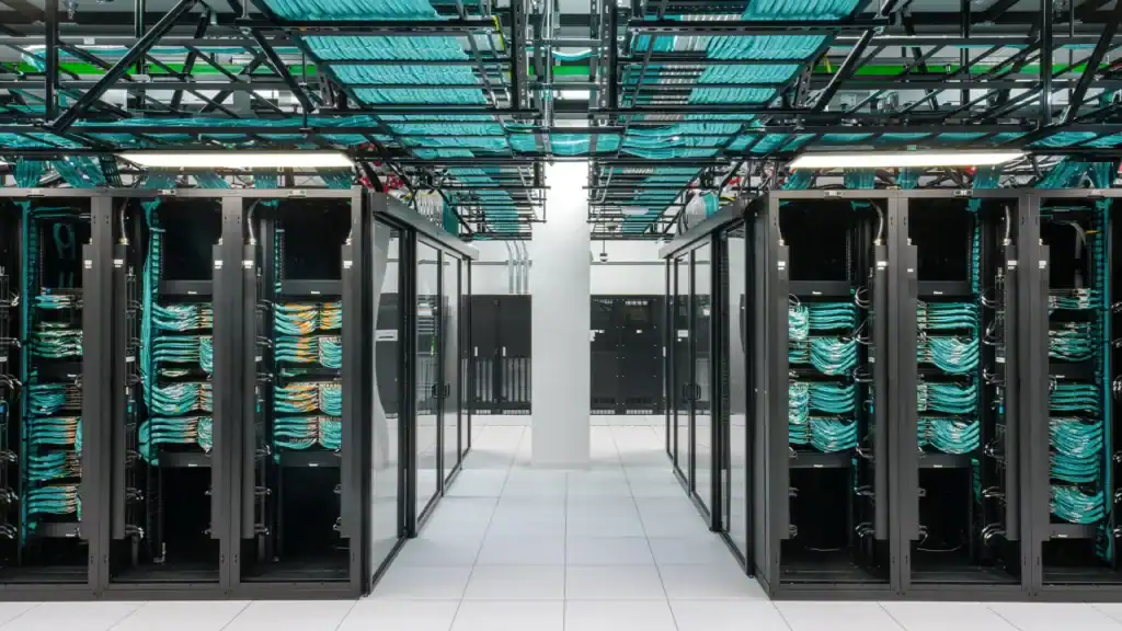 Rows of densely packed GPU server racks inside a data center with glowing indicator lights and cable management systems visible